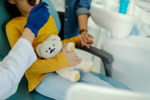 歯科医院でぬいぐるみを持って治療を受けている子供