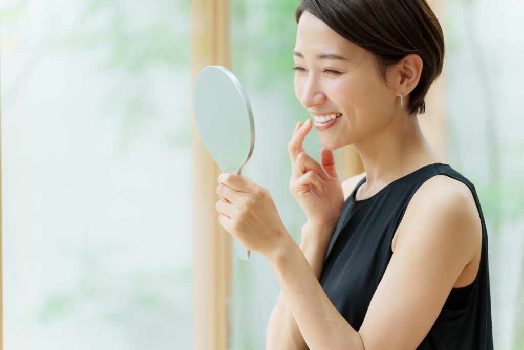 鏡で自分の歯を確認している女性