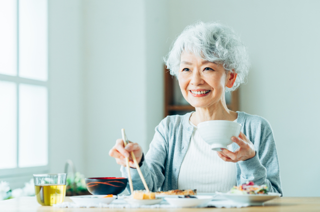 入れ歯のメンテナンスを保ち快適な口腔環境で食事をいただく女性