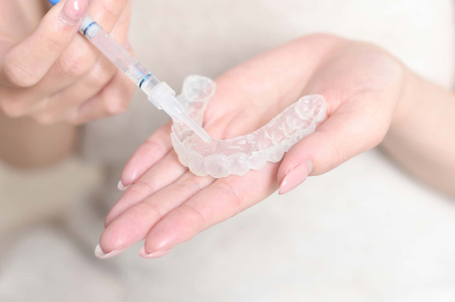 ホームホワイトニングに使用するマウスピースとジェル薬品の入ったシリンジを手に持っているイメージ