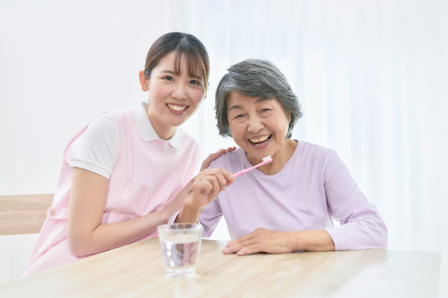 訪問歯科で口腔ケアの指導をする歯科衛生士と笑顔で受ける女性