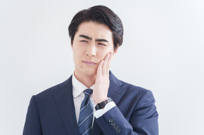 顎関節に違和感を感じ手を当てる男性