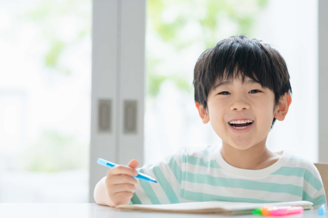 悪い歯並びを治療して笑顔で勉強をする子ども