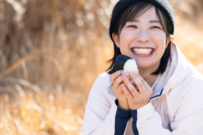 笑顔でおにぎりを食べる女性