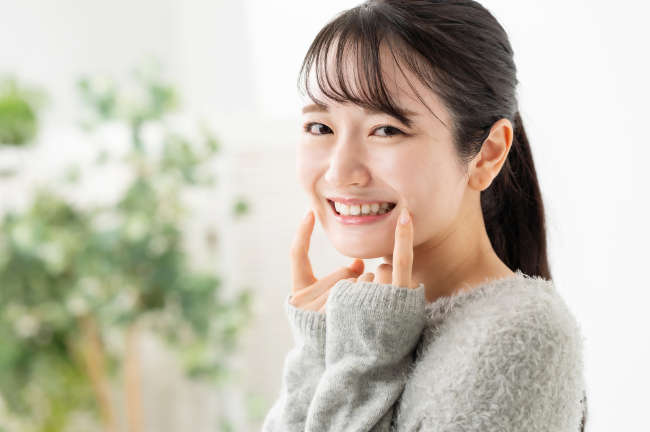 親知らずを指さして笑顔を見せる女性
